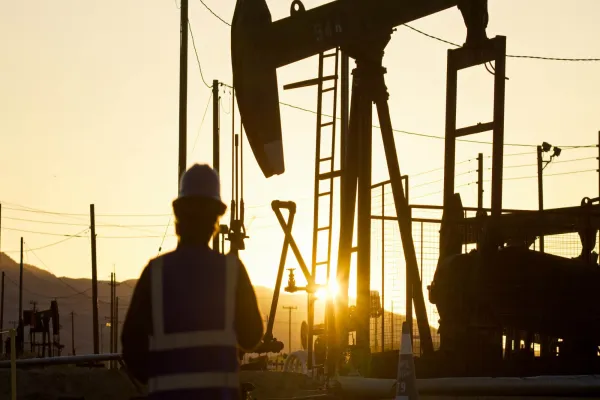 Oilfield Worker Facing Oil Pump Jack at Sunset