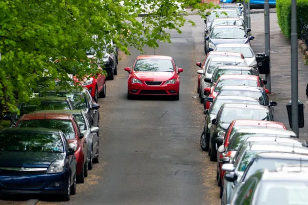 Car in the middle of a road with cars parked on either side, Scotland, UK