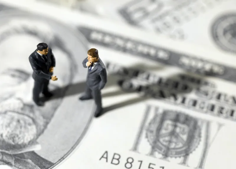 toy businessmen on US paper currency